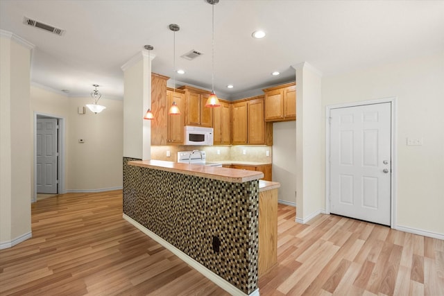 143 Doe Run Rd, Gun Barrel City, TX 75156 - kitchen with white microwave, a peninsula, light wood finished floors, backsplash, and baseboards