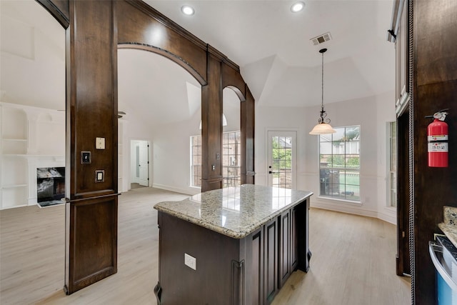 8209 Shoshoni Dr, Arlington, TX 76002 - kitchen with light wood-style floors, high vaulted ceiling, dark brown cabinets, hanging light fixtures, and light stone counters
