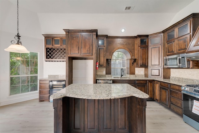 8209 Shoshoni Dr, Arlington, TX 76002 - kitchen featuring stainless steel appliances, a sink, light wood-style floors, decorative backsplash, and a kitchen island