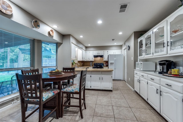 4920 Brookhollow Dr, Sachse, TX 75048 - kitchen featuring white appliances, under cabinet range hood, white cabinets, glass insert cabinets, and tasteful backsplash