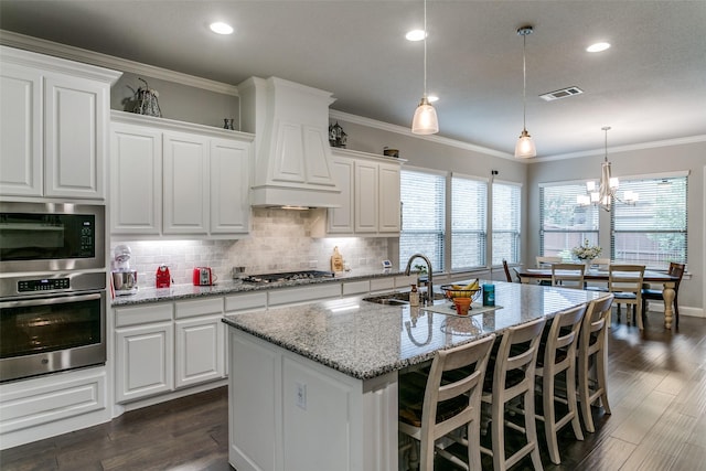 6929 Heather Ln, North Richland Hills, TX 76182 - kitchen featuring appliances with stainless steel finishes, custom range hood, backsplash, light stone counters, and crown molding