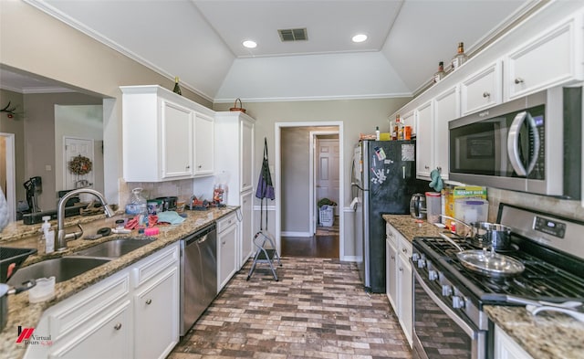 6008 Pepperwood Cir, Bossier City, LA 71111 - kitchen featuring appliances with stainless steel finishes, a sink, white cabinets, vaulted ceiling, and brick patterned flooring