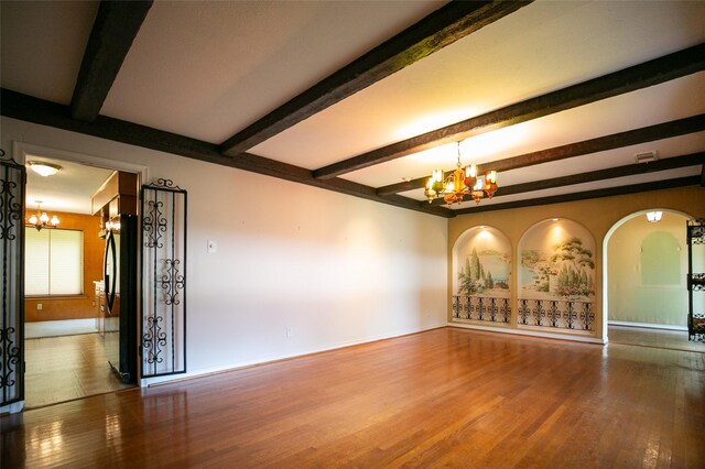 10210 E Lk Highlands, Dallas, TX 75218 - unfurnished room with a chandelier, wood finished floors, beamed ceiling, baseboards, and arched walkways