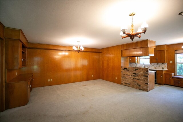 10210 E Lk Highlands, Dallas, TX 75218 - kitchen featuring a chandelier, brown cabinets, light carpet, wooden walls, and decorative light fixtures