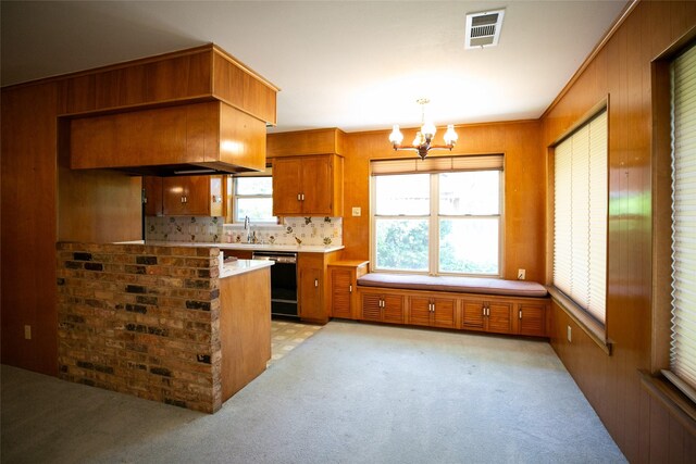 10210 E Lk Highlands, Dallas, TX 75218 - kitchen featuring black dishwasher, brown cabinets, a chandelier, a sink, and wooden walls