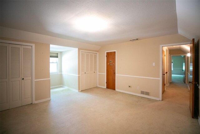 10210 E Lk Highlands, Dallas, TX 75218 - unfurnished bedroom featuring two closets, light carpet, baseboards, and lofted ceiling