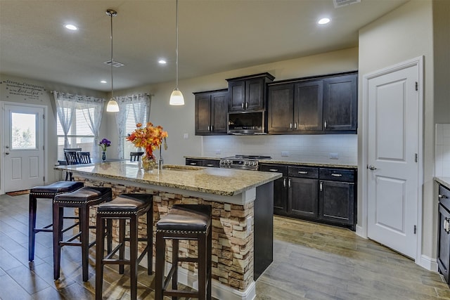 1541 Seabiscuit Dr, Granbury, TX 76049 - kitchen with stainless steel appliances, light wood-type flooring, a sink, a breakfast bar, and tasteful backsplash