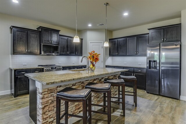 1541 Seabiscuit Dr, Granbury, TX 76049 - kitchen with stainless steel appliances, light wood-type flooring, a sink, a breakfast bar, and tasteful backsplash