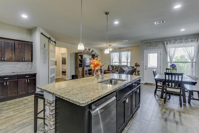 1541 Seabiscuit Dr, Granbury, TX 76049 - kitchen featuring a sink, dishwasher, a barn door, ceiling fan, and backsplash