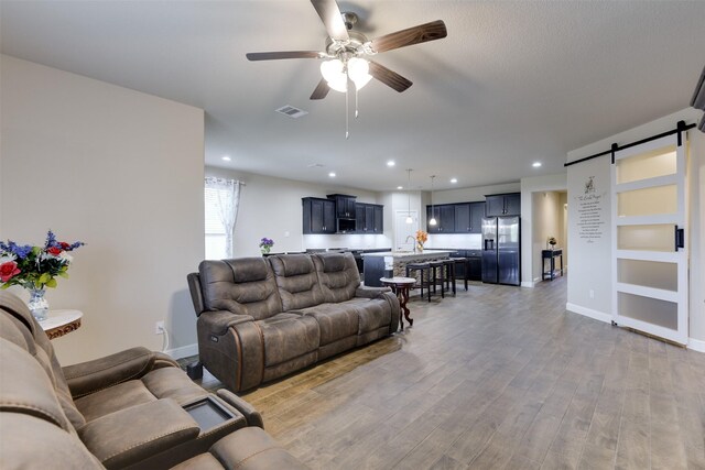 1541 Seabiscuit Dr, Granbury, TX 76049 - living area featuring a barn door, a ceiling fan, recessed lighting, light wood finished floors, and baseboards