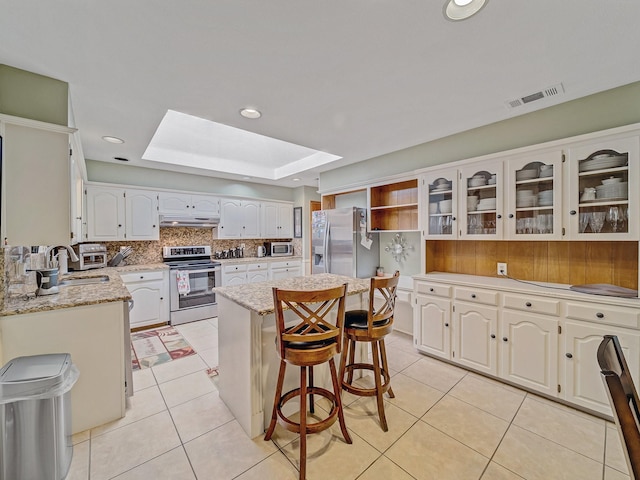 4640 Versailles Ln, Plano, TX 75093 - kitchen featuring stainless steel appliances, a sink, under cabinet range hood, a tray ceiling, and a kitchen island