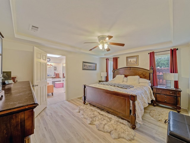 4640 Versailles Ln, Plano, TX 75093 - bedroom featuring a raised ceiling, light wood-style floors, ensuite bathroom, and ceiling fan