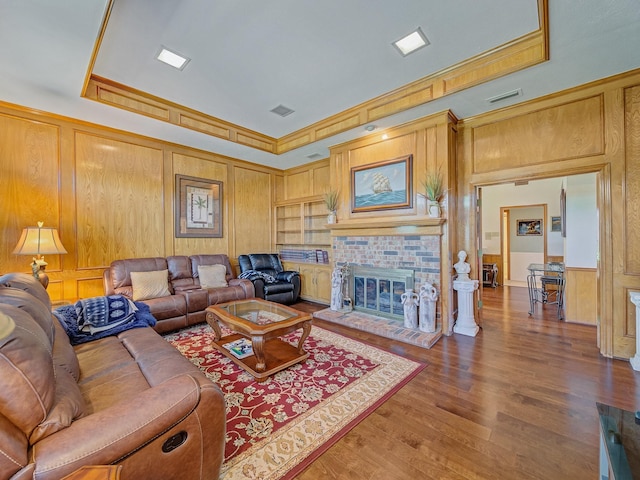 4640 Versailles Ln, Plano, TX 75093 - living area with wood finished floors, wooden walls, crown molding, a raised ceiling, and a fireplace