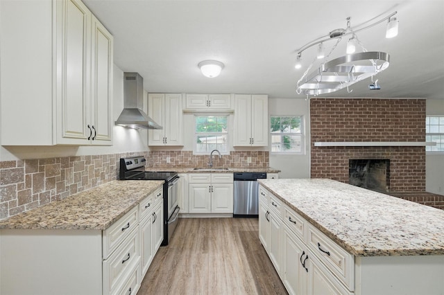 325 Belmont St, Hurst, TX 76053 - kitchen with stainless steel appliances, wall chimney range hood, light stone countertops, and light wood-type flooring