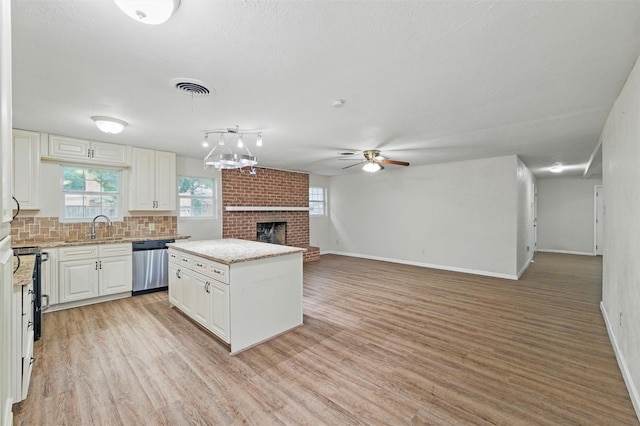 325 Belmont St, Hurst, TX 76053 - kitchen featuring dishwasher, a fireplace, ceiling fan, white cabinets, and light wood-style flooring