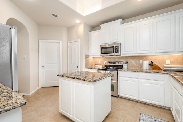 7609 Velvet Antler Trl, Arlington, TX 76002 - kitchen featuring appliances with stainless steel finishes, arched walkways, a center island, decorative backsplash, and recessed lighting