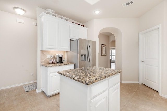 7609 Velvet Antler Trl, Arlington, TX 76002 - kitchen with stainless steel refrigerator with ice dispenser, arched walkways, light stone counters, light tile patterned flooring, and white cabinetry