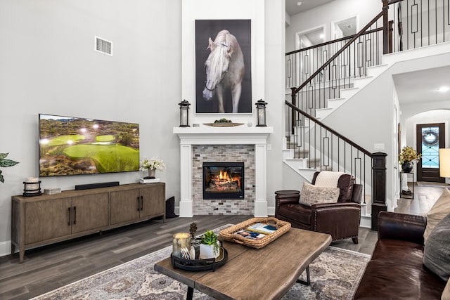 16471 Prairie Oak Rd, Frisco, TX 75033 - living area with a towering ceiling, wood finished floors, stairs, a tile fireplace, and arched walkways