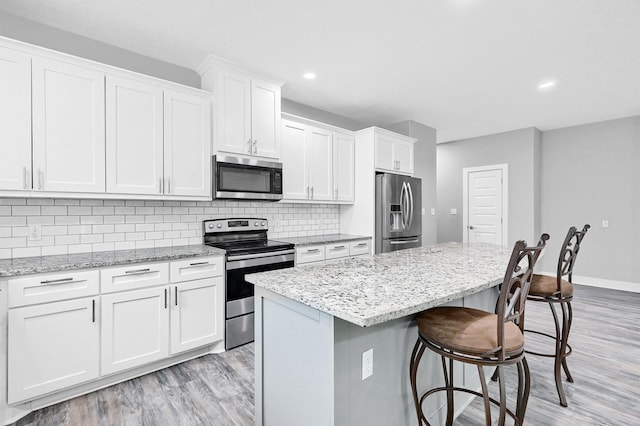 615 W Brock St, Denison, TX 75020 - kitchen with stainless steel appliances, light wood-type flooring, a breakfast bar, white cabinetry, and backsplash