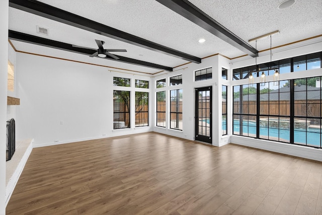 4000 Tumbril Ln, Plano, TX 75023 - unfurnished living room with a textured ceiling, beamed ceiling, a ceiling fan, wood finished floors, and plenty of natural light