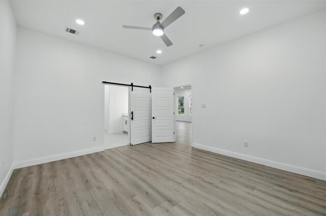 3220 N Houston, Fort Worth, TX 76106 - unfurnished bedroom with a barn door, light wood-style flooring, baseboards, recessed lighting, and ensuite bathroom