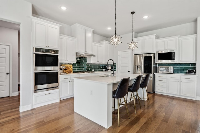 719 Forefront Ave, Celina, TX 75009 - kitchen featuring appliances with stainless steel finishes, a sink, backsplash, a breakfast bar, and a kitchen island with sink