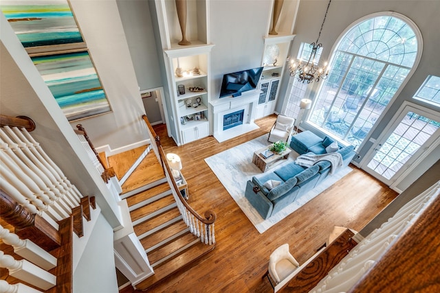 9352 Stratford Way, Dallas, TX 75220 - living area with wood finished floors, a fireplace with raised hearth, a high ceiling, stairway, and healthy amount of natural light