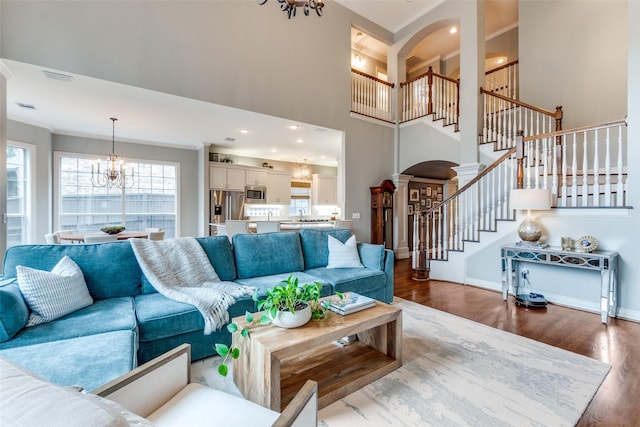 9352 Stratford Way, Dallas, TX 75220 - living area featuring ornamental molding, a chandelier, dark wood-style flooring, stairway, and arched walkways