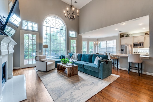 9352 Stratford Way, Dallas, TX 75220 - living room featuring a chandelier, healthy amount of natural light, wood finished floors, a fireplace, and high vaulted ceiling
