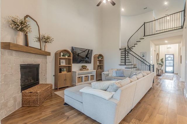 1050 Adair Rd, Prosper, TX 75078 - living room with a high ceiling, stairs, wood finished floors, a stone fireplace, and ceiling fan