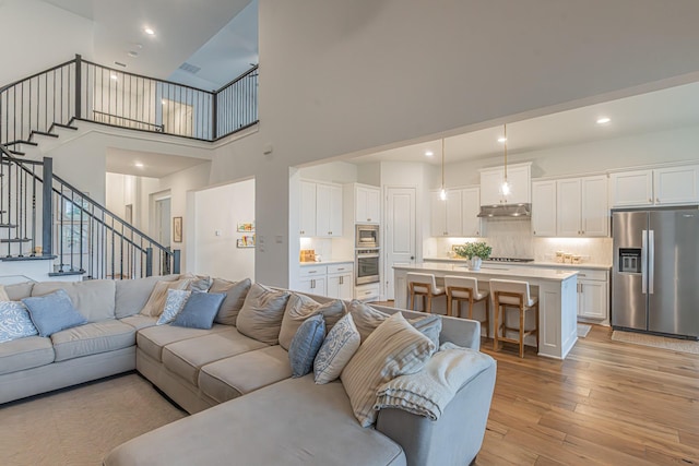 1050 Adair Rd, Prosper, TX 75078 - living room with stairs, a high ceiling, light wood-style flooring, and recessed lighting