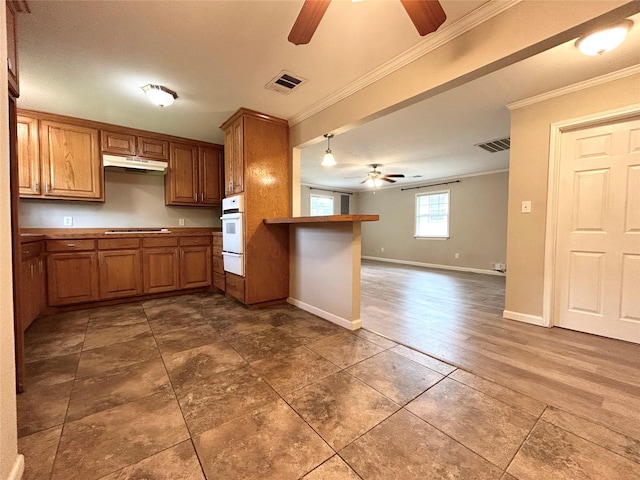 125 Park St E, Sulphur Springs, TX 75482 - kitchen featuring ceiling fan, crown molding, oven, brown cabinets, and a warming drawer