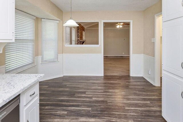 1425 Bryan Dr, Bedford, TX 76022 - unfurnished dining area with a wainscoted wall, ceiling fan, dark wood-style flooring, and a textured ceiling