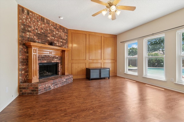 1302 Woodmont Dr, Allen, TX 75002 - unfurnished living room with wood finished floors, a brick fireplace, a ceiling fan, baseboards, and a textured ceiling