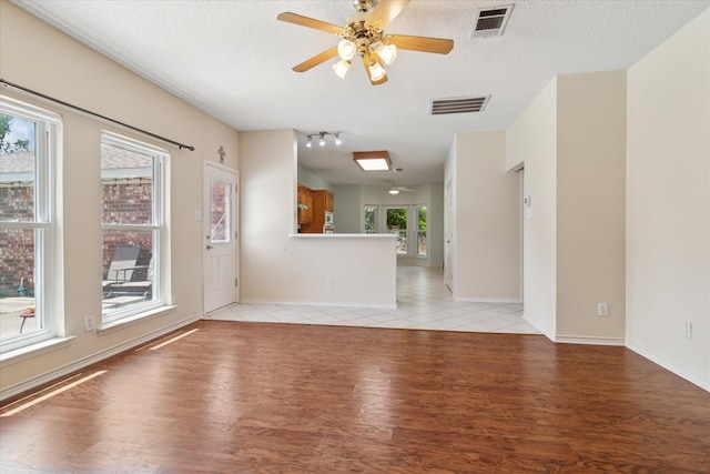 1302 Woodmont Dr, Allen, TX 75002 - unfurnished living room featuring light wood finished floors, a textured ceiling, a ceiling fan, and baseboards