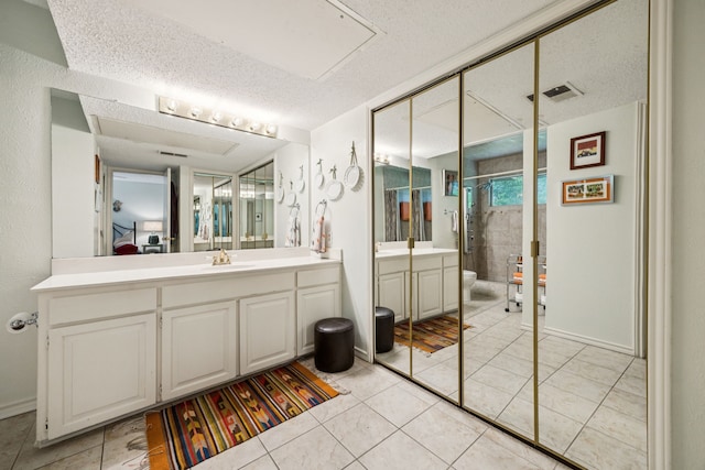 9222 Church Rd Unit 108, Dallas, TX 75231 - bathroom with vanity, a shower stall, a textured ceiling, tile patterned flooring, and toilet