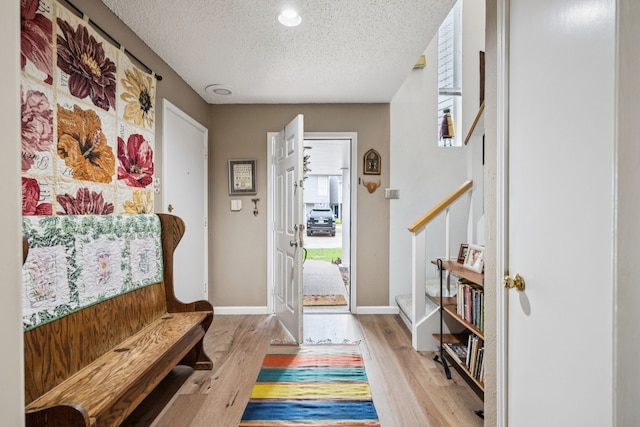 9222 Church Rd Unit 108, Dallas, TX 75231 - entryway featuring a textured ceiling, light wood-type flooring, baseboards, and stairs