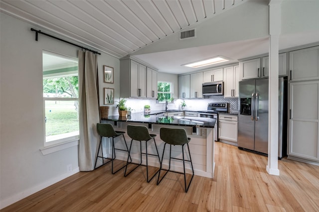 1410 Traildust Dr, Lowry Crossing, TX 75069 - kitchen with appliances with stainless steel finishes, a peninsula, light wood-style floors, a breakfast bar area, and lofted ceiling