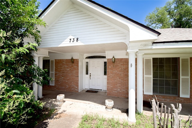 738 Westwood Dr, Marlin, TX 76661 - doorway to property with brick siding, a porch, and roof with shingles