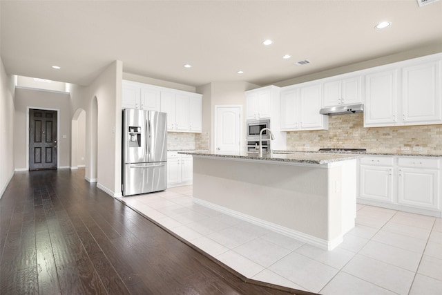 4104 Portola Dr, Mckinney, TX 75070 - kitchen featuring stainless steel appliances, arched walkways, backsplash, white cabinetry, and light stone counters