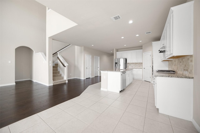 4104 Portola Dr, Mckinney, TX 75070 - kitchen featuring light tile patterned floors, open floor plan, stainless steel appliances, backsplash, and an island with sink