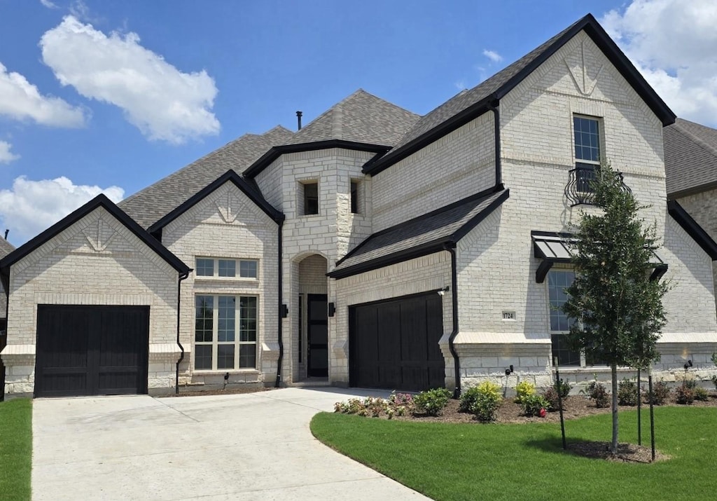 1724 Ruby Way, Rockwall, TX 75087 - french country home featuring concrete driveway, a shingled roof, brick siding, and a front yard