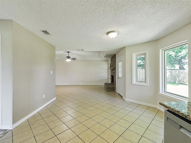7275 Fm 455 W, Sanger, TX 76266 - empty room featuring a brick fireplace, ceiling fan, light tile patterned flooring, baseboards, and a textured ceiling