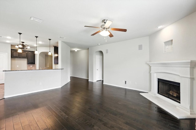 3112 Stonecrop Trl, Denton, TX 76226 - unfurnished living room with ceiling fan, recessed lighting, dark wood-style flooring, a fireplace with raised hearth, and arched walkways