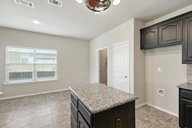 3112 Stonecrop Trl, Denton, TX 76226 - kitchen with a center island, light stone counters, light tile patterned floors, and dark brown cabinets