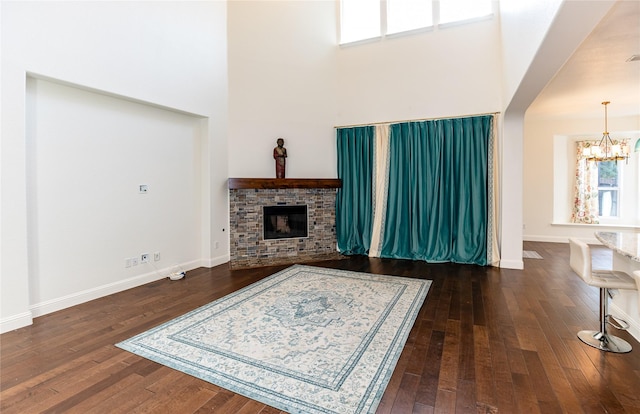 6925 Mercy Rd, Frisco, TX 75035 - living area featuring a chandelier, a towering ceiling, wood-type flooring, a stone fireplace, and baseboards
