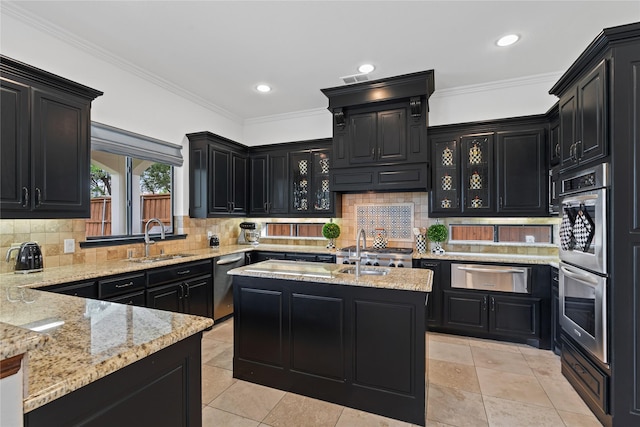 10388 Tobias Ln, Frisco, TX 75033 - kitchen with dark cabinetry, a sink, appliances with stainless steel finishes, a warming drawer, and light stone counters