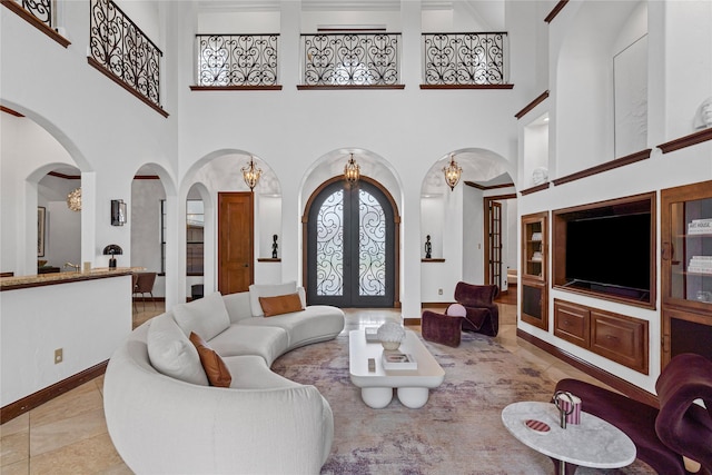 10388 Tobias Ln, Frisco, TX 75033 - living room with arched walkways, french doors, a towering ceiling, a chandelier, and baseboards