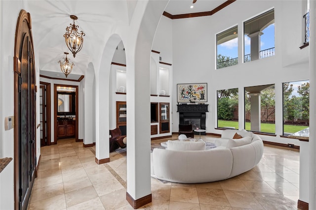 10388 Tobias Ln, Frisco, TX 75033 - living area with baseboards, crown molding, a glass covered fireplace, arched walkways, and a high ceiling
