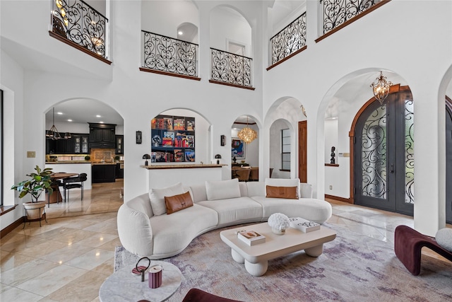 10388 Tobias Ln, Frisco, TX 75033 - living room with arched walkways, a chandelier, a high ceiling, baseboards, and french doors